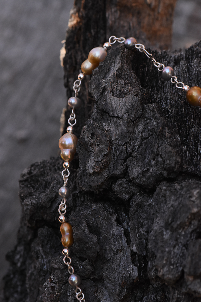 A closeup photo of necklace made from sterling silver and freshwater pearls